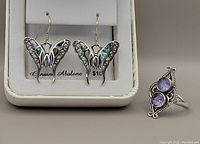 Earrings and ring displayed side-by-side showing the butterfly design with abalone shell and purple stones on the ring