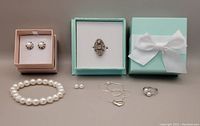 Full lot arranged, showing two rings, necklace chain, pearl bracelet, two pairs of pearl earrings in gift boxes