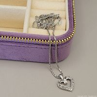 White gold chain necklace with heart pendant displayed in open purple velvet box