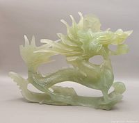 Front side view of the translucent pale green nephrite hand-carved dragon showing detailed scales and flowing mane.