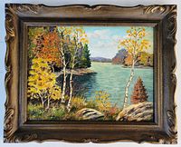 Framed oil painting showing full artwork of autumn trees and lake with decorative brown frame.