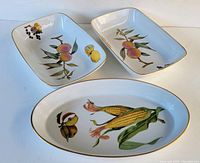 Top view of all three porcelain serving pieces arranged together showing fruit and vegetable decorations.