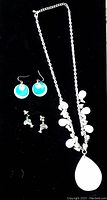 Silver-tone necklace and two pairs of abalone shell earrings on black background, showing entire jewelry set.