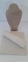 Front view of necklace bust display alongside bracelet roll and flat platform covered in beige fabric