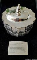 Photo of silver decorative box with lid showing reflective surface and finial knob, along with a card explaining the Museum Re-Creations line.