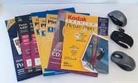 Various unopened packs of labels and photo paper arranged in a fan shape, showing multiple brands including Kodak and Memorex