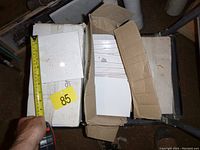 Boxes of white ceramic bathroom wall tiles labeled 'enigma', some boxes opened showing tiles inside.