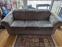 Front view of the light brown couch showing three seat cushions and curved armrests.