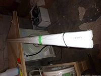 Two white IKEA HUGAD curtain rods wrapped together on top of a dryer in a dimly lit room.