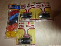 Three packaged Long Power Back Buzzers and a sealed package of colored test leads on a wooden surface.