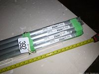 Seven bundled metal curtain tracks with IKEA KVARTAL labels visible, measuring tape and green tape around them.