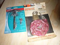 Photo showing the two packaged items: Ideal brand chrome locking handle for garage door with key, and Supercycle heavy duty bicycle chain lock with pink plastic cover and padlock with key on a card backing from Canadian Tire.