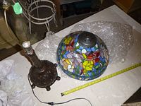 Disassembled view of stained glass shade and cast metal base laid on table