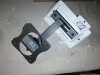 Small TV mount arm with square swivel bracket and white wall plate, shown from above on table.