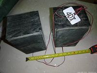 Two Sony speakers placed on floor with measuring tape for length showing about 9 inches