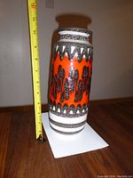 Front view of the tall ceramic vase measuring about 11 inches high, showing bright orange base with black and white textured patterns