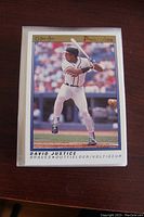 Front view of a 1990 OPC Premiere David Justice outfielder baseball card featuring player batting in stadium.