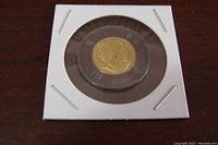 Front view of the 2022 Canadian $2 coin featuring Queen Elizabeth II effigy with black mourning ring, housed in protective holder.