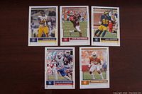Five NFL rookie trading cards laid out on a dark wood surface, featuring Kareem Hunt, DeDe Westbrook, Jenius Chesson, Carlos Henderson, and Cameron Sutton.