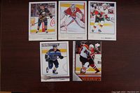 Top-down image showing 5 mint condition NHL rookie hockey cards from various teams displayed on a dark surface.