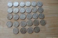 Top view of 28 replica Morgan dollar coins arranged in rows showing front faces with Lady Liberty detail.