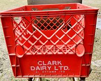 Close-up photo showing front side of a single red resin milk crate with embossed white branding 'CLARK DAIRY LTD. OTTAWA - 73'.