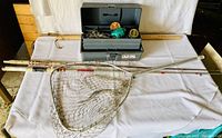 Full view of fishing rods, net, and open tackle box on table with measuring stick