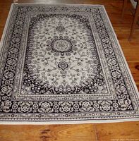 Full view of rectangular rug laid on wood floor, showing detailed pattern and border design.