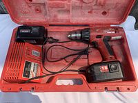 View of the drill, charger, one battery attached to drill, another battery next to charger inside the carrying case.