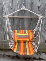Front view of portable hanging chair hammock showing wooden support bar and multi-color striped fabric seat with attached pocket and rope suspension.