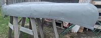 Side view of the aluminum canoe showing gray painted surface and repaired areas.