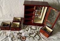 Jewelry box with drawers open showing jewelry inside, assorted necklaces and bracelets laid out in front