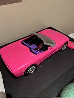 Side angled view showing pink Corvette body, purple seats, and convertible style top.