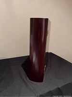 Side view of vertical wooden storage box with a curved edge, finished in dark brown wood stain.
