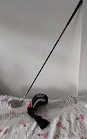 Photo of the full Callaway Big Bertha 460 golf driver with black shaft and included headcover lying on a bed.