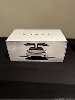 Box front showing Tesla logo and car with doors open.