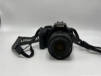 Front view of Canon EOS Rebel XTi camera with attached EF-S 18-55mm lens and neck strap.