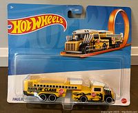 Front photo of sealed Hot Wheels Haulin Class school bus toy in blister pack, showing yellow school bus with flames and stop sign.
