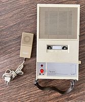 Front view of beige Sears cassette recorder showing speaker grill, cassette window, controls and attached microphone with cord.