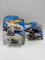 Two Hot Wheels cars in original packaging: Mountain Mauler on left and The Outlawer on right.