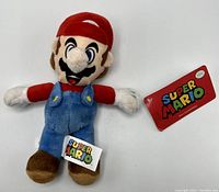 Front view of Super Mario plush showing attached colorful tags.