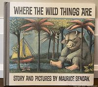 Front cover of the book showing title and illustration of a large creature seated among palm trees with a small sailing boat in the background.
