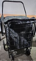 View of the front of the cart showing the black fabric liner and Velcro seal rain cover, with metal frame and handle grip.