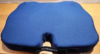 Blue ergonomic seat cushion with central cut-out and brand label KABOOTI.
