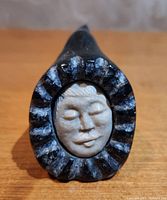 Front view showing the woman's face with scalloped black stone hood.