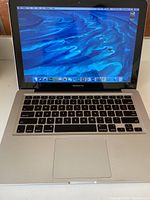 Front view of MacBook Pro powered on showing screen and keyboard with trackpad.
