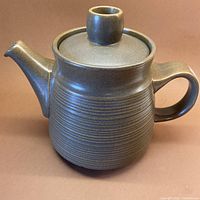 Full view of teapot with lid in place on brown background
