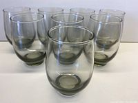 Photo showing eight smoky grey glasses grouped together, arranged with one glass in front and seven behind in two rows.