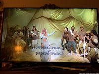 Front view showing TV powered on playing a music performance video with on-screen captions.