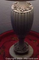 Close-up of vase body showing ribbed texture and floral and berry wreath embellishments, greyish onyx white finish with minor chips.